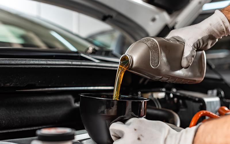 A person pouring oil into a funnel